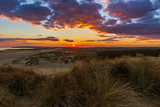 Fototapeta Krajobraz - The sun setting over the high weald of east Sussex from the dunes of Camber Sands one beautiful March evening.