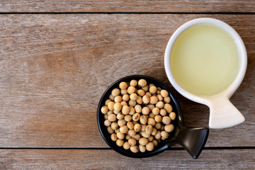 Wall Mural - Soy bean oil with soybean seeds in black and white ceramics bowl isolated on rustic wood table background. Overhead view. Flat lay.