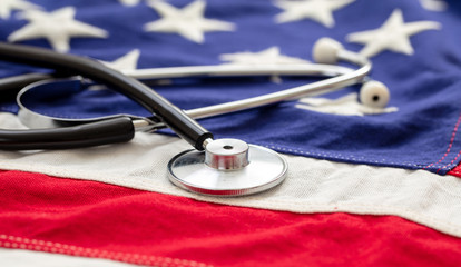 US of America health. Medical stethoscope on a USA flag, closeup view.