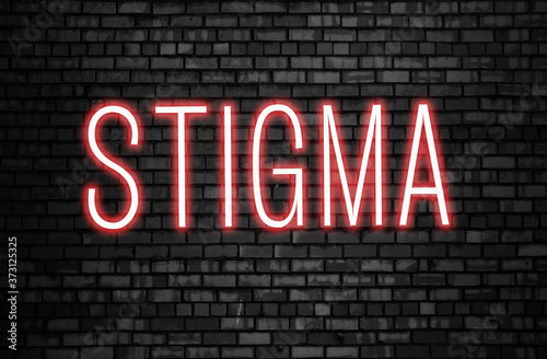 Stigma glowing neon word on black brick wall. Tolerance concept