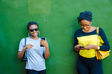 Fototapeta Łazienka - two beautiful african ladies operating their cellphone