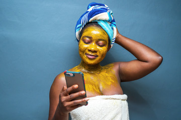 Canvas Print - Closeup shot of a female in a towel wearing a mask and holding a phone