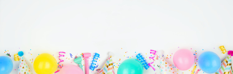 Wall Mural - Birthday party banner with bottom border on a white background. Top down view with balloons, party hats, streamers and confetti. Copy space.