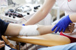 © AnnaStills - Close-up of patient with bandaged hand donating blood with nurse working with him