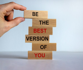 Male hand placing a block with word 'be' on top of a blocks tower with words 'be the best version of you'. Beautiful white background. Copy space.