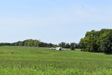 Canvas Print - Farm Field with a Livestock Trailer and Hay Bales