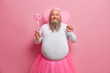 © wayhome.studio  - Positive plump man has fun on theme birthday party, feels like fairy who makes dreams come true, chills with children, has thick beard and fat belly, poses with magic wand and wings on back.