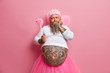 © wayhome.studio  - Serious male tooth fairy with big tattooed belly, wears rosy wings, holds magic wand and looks thoughtfully aside, thinks how to entertain childen during holiday, isolated on pink background