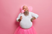 Serious Bearded Man Thinks How To Entertain Children On Party, Wears Funny Costume Of Princess Or Fairy, Concentrated Thoughtfully Aside. Family, Celebration, Fatherhood, Entertainment Concept