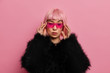 © WHstudio Leushin N - Gorgeous self confident serious woman wears trendy pink sunglasses, has rosy bob hair, dressed in fluffy warm black sweater, stands indoor, thinks about something. Women, fashion, style concept