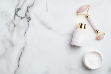 Wall Mural - face skin care concept. quartz facial massager, lotion bottle, moisturizer cream on marble desk. ant