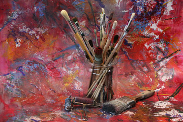 Glass jar with various painting brush on an abstract background