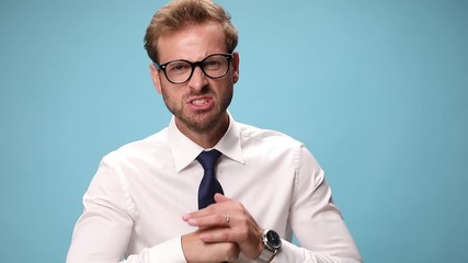 Wall Mural - angry businessman pointing at the camera, fisting his palm and threatening on blue background