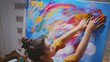 © DC Studio - Woman using hand fingers while painting on large canvas in art studio.