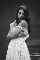 Sticker - Grayscale shot of beautiful young lady wearing a wedding dress and a tiara, posing in the water