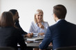 © fizkes - Successful negotiations. Happy smiling businesswoman reaching agreement with multiethnic corporate partners, glad older female team leader discussing good work results with younger diverse colleagues