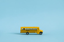 Back To School Concept. Traditional Yellow School Bus On Blue Background. Transfer To School. Yellow Toy Model School Bus.
