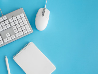 Poster - top view of office desk table with notebook, plastic plant, smartphone and keyboard on blue table background, graphic designer, Creative Designer concept.