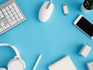 Poster - top view of office desk table with notebook, plastic plant, smartphone and keyboard on blue table background, graphic designer, Creative Designer concept.