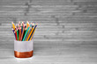 Colored pencils in a plaster cup on a natural, white background made of wooden boards. Website concept, school related topic.