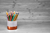 Fototapeta Niebo - Colored pencils in a plaster cup on a natural, white background made of wooden boards. Website concept, school related topic.