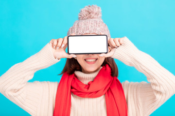 Smiling young woman in winter dress and showing  smart phone