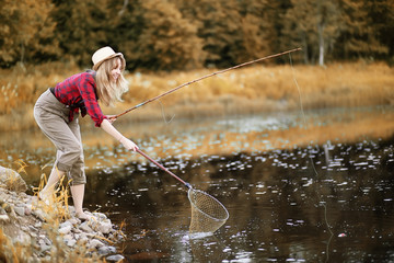 Girl in autumn with a fishing rod