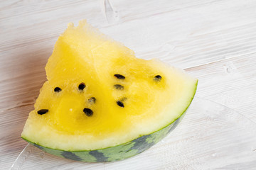 piece of yellow watermelon on white wooden table background.