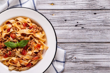 Wall Mural - Traditional italian pasta bolognese on a white plate on a wooden background