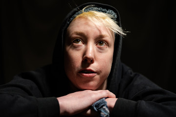 Portrait of a young woman with short blonde hair and black hoodie.