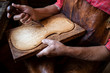 Close up view of carpenter's hands shaping and carving wood in his old-fashion workshop. Craftsman holding carving knife embossing hardwood.
