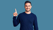 © Krakenimages.com - Young handsome man wearing casual clothes showing and pointing up with finger number one while smiling confident and happy.