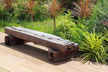 Bench Made From An Old Wooden Railway Sleeper With A Background Of A Green Tropical Garden In Bright Sunshine
