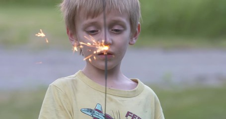 cute little boy holding a sparkler.