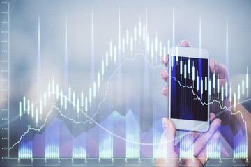 Double exposure of forex graph sketch hologram and woman holding and using a mobile device. Stock market concept.