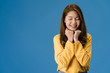 © tirachard - Young Asia lady with positive expression, smile broadly, dressed in casual clothing and close your eyes over blue background. Happy adorable glad woman rejoices success. Facial expression concept.