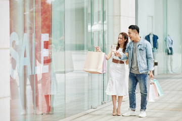 Sticker - Young Vietnamese couple shopping in mall on weeked, walking and looking through shop window