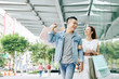 © DragonImages - Cheerful young Vietnamese couple walking in the street after shopping in mall on weekend