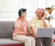 Asian senior couple having goodtime together , listen to the music from headphones with computer laptop on lap. Elderly lifestyle concept.