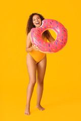 Sticker - Beautiful young African-American woman with inflatable ring on color background