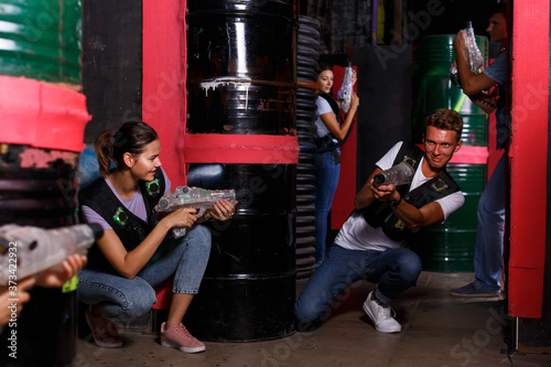 Portrait of happy young friends playing laser tag game with laser guns in dark room Poster Mural XXL