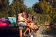 © Zoran Zeremski - Group of young friends sitting on the edge of a pier having fun and enjoying a summer day at the lake.