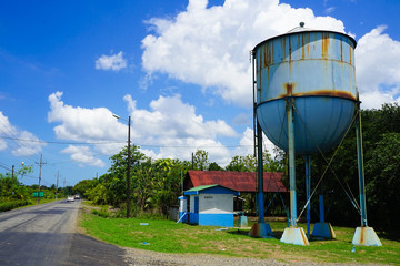 Wall Mural - Low angle shot of a rusty water tank on the side of the road during a sunny day