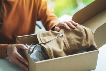 A woman receiving and opening a postal parcel box of clothing at home for delivery and online shopping concept