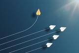 paper planes flying in formation in one direction on blue background and one paper glider going in different direction, breaking new ground and stepping out of the line concept