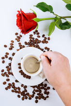Cup Of Coffee And A Red Rose. Coffee Beans Scattered On The Table.