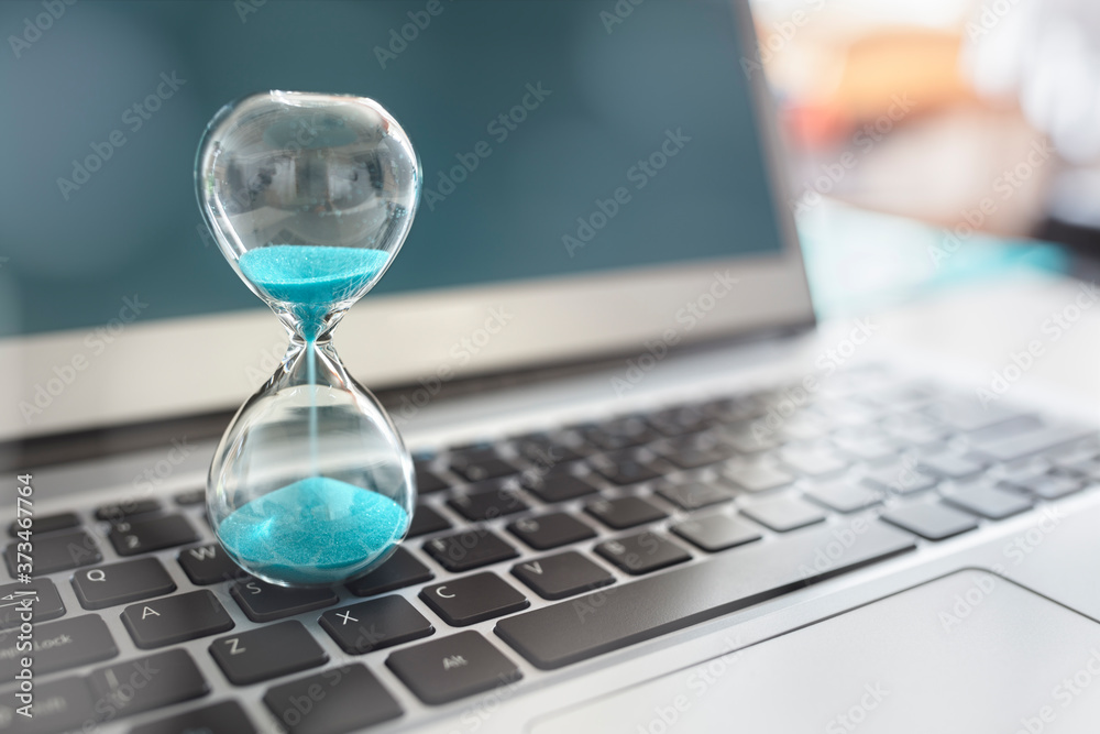 Hourglass on laptop computer concept for time management - obrazy, fototapety, plakaty 