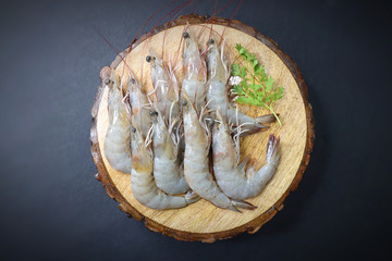 Wall Mural - fresh shrimps or white prawns raw on wooden chopping board with coriander and curry leaves. on background with copy space.