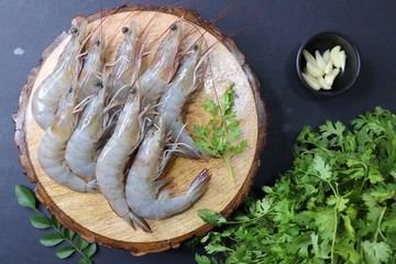 Wall Mural - fresh shrimps or white prawns raw on wooden chopping board with coriander and curry leaves. on background with copy space.