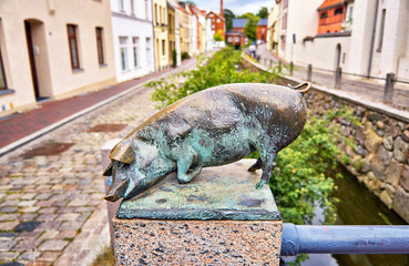 Lying pig as a bronze statue on the canal bridge in the city of Wismar.